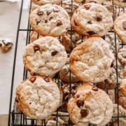 chocolate chips cookies on a cooling rack with more dough on a cookie sheet