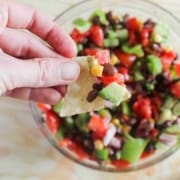 Hand raising a chip with salsa on it